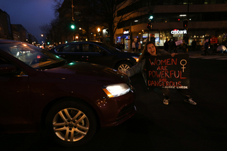 Tara McManus attempts to stop a car from proceeding down K Street in an effort to halt the flow of traffic during the Women's March on Washington.