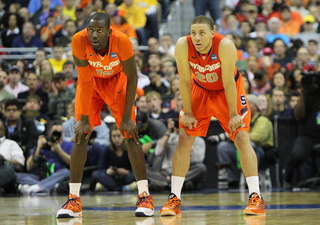 Baye Moussa-Keita #12 of the Syracuse Orange looks on with teamate Brandon Triche #20.