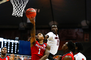 Lacey tries to finish a reverse layup with his right hand while Mathiang defends.